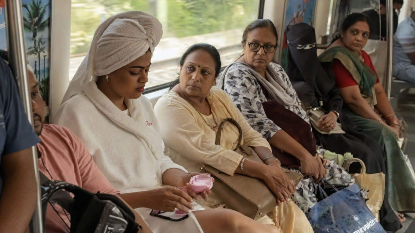Woman does skincare routine in bathrobe on Delhi Metro