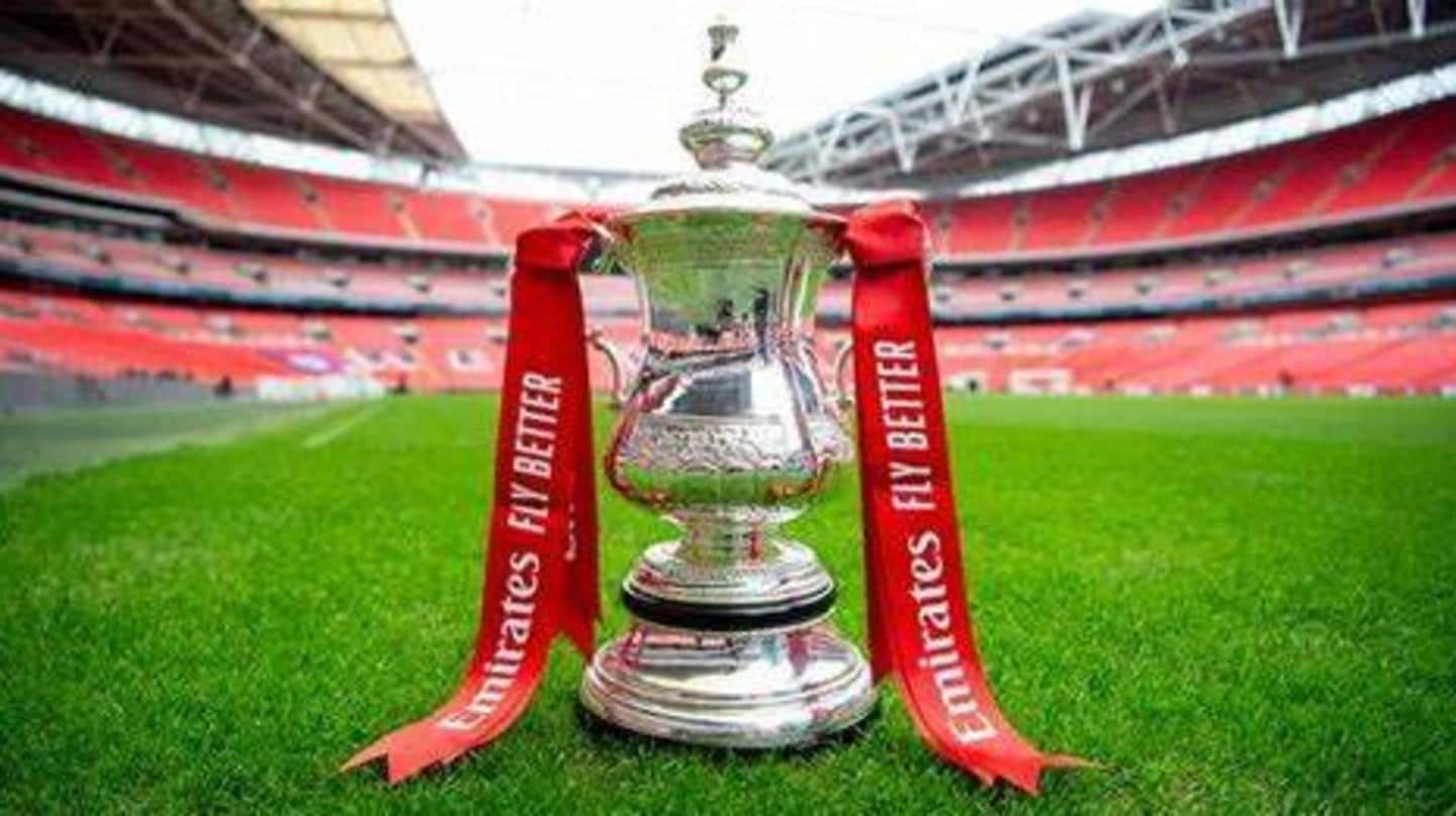  The image shows the Emirates FA Cup trophy with a green and white background.