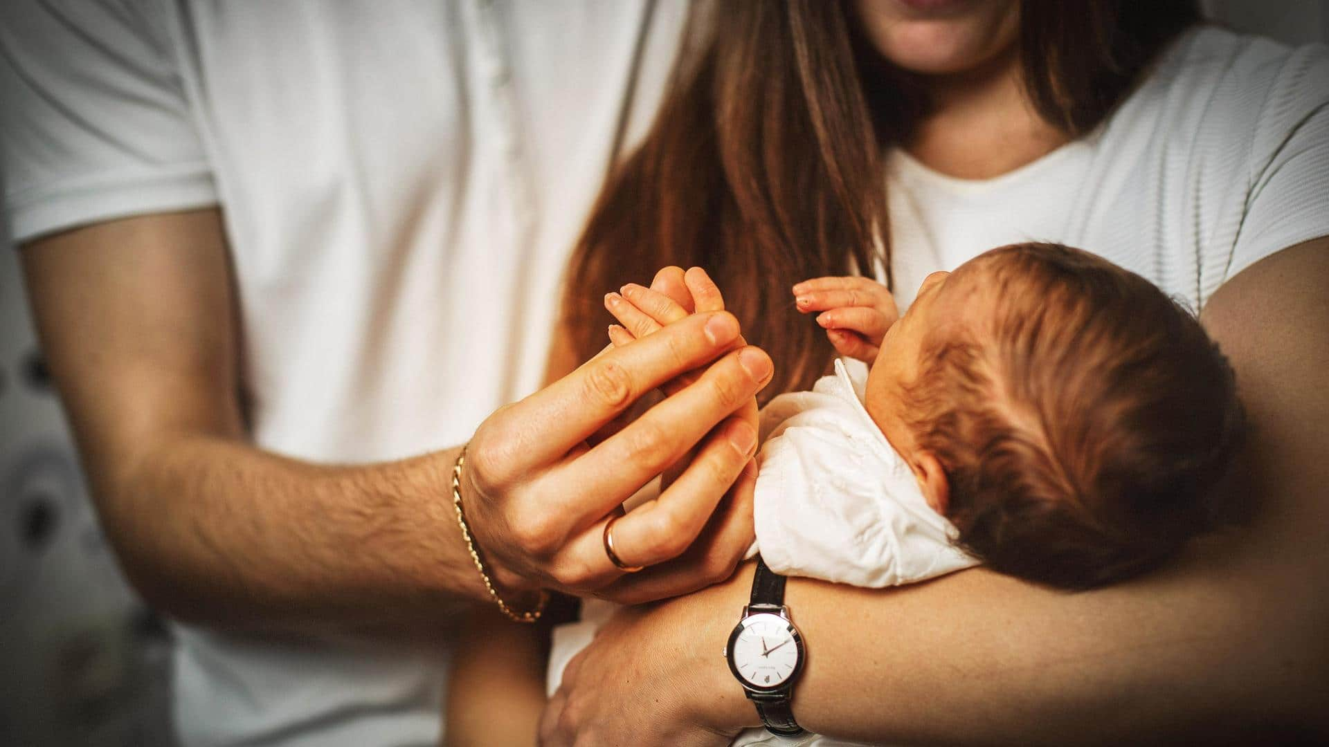 Mom nursing newborn while dad and big sister watch Stock Photo - Alamy