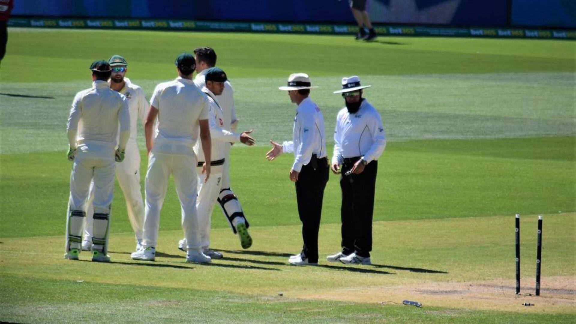 Mengapa wasit kriket memakai topi saat pertandingan?